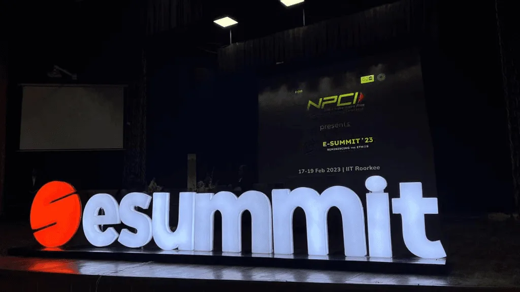 Illuminated esummit letter sign on a dark stage in front of a backdrop screen reading E-Summit '23, 17-19 Feb 2023, IIT Roorkee